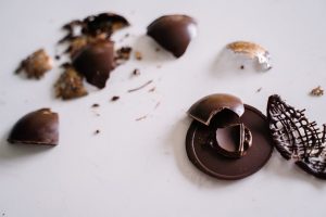 Close-up of broken chocolate pieces scattered on a white surface, perfect for food photography.