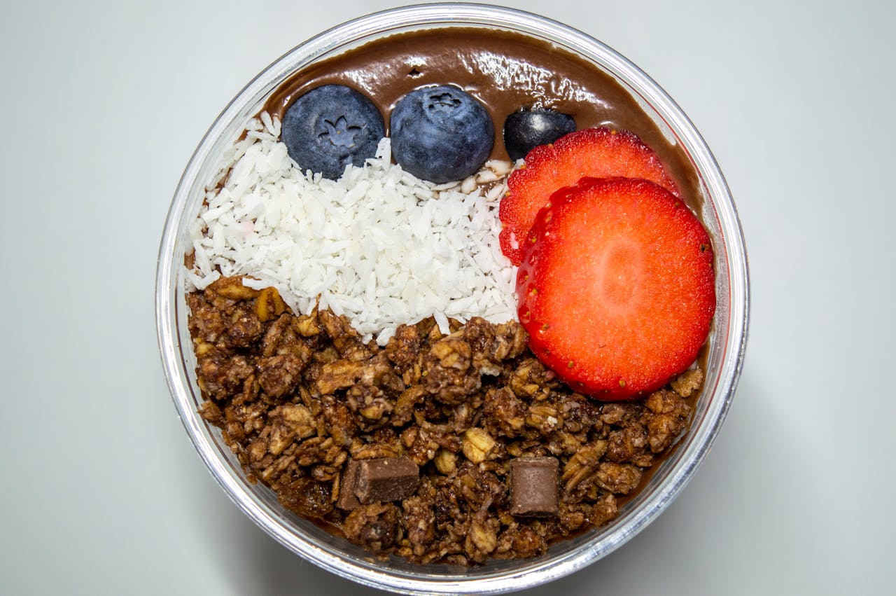 Delicious chocolate smoothie bowl topped with blueberries, strawberries, coconut, and granola, perfect for a nutritious breakfast.