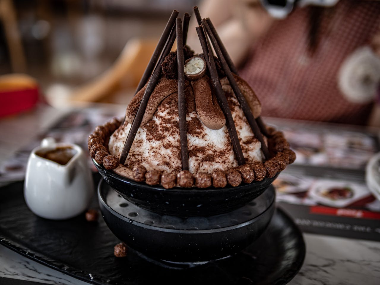 A delectable chocolate-topped ice cream dessert in a stylish black bowl, perfect for gourmet food lovers.